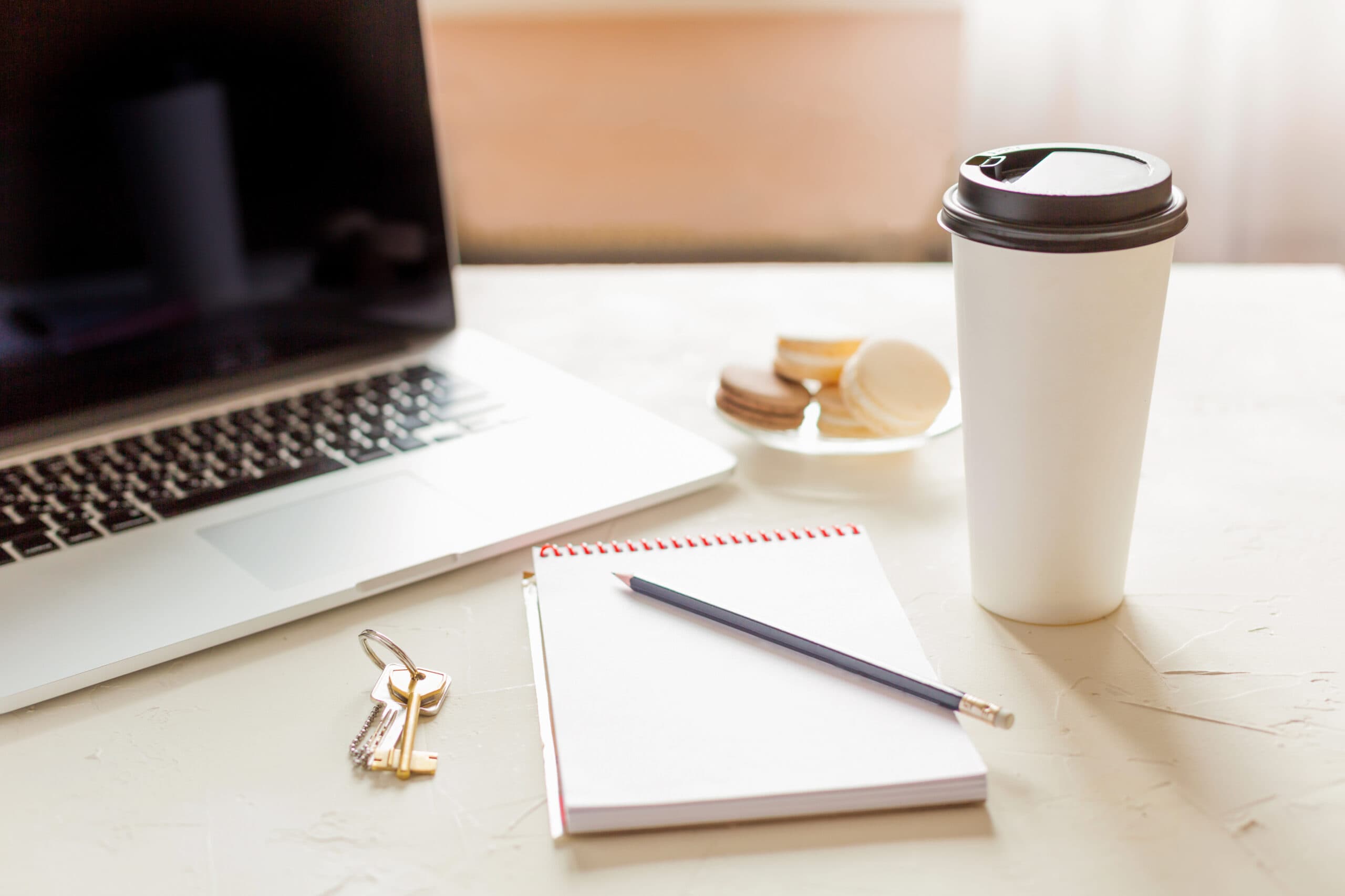 Laptop, notatnik, ciasteczka oraz kubek z kawą