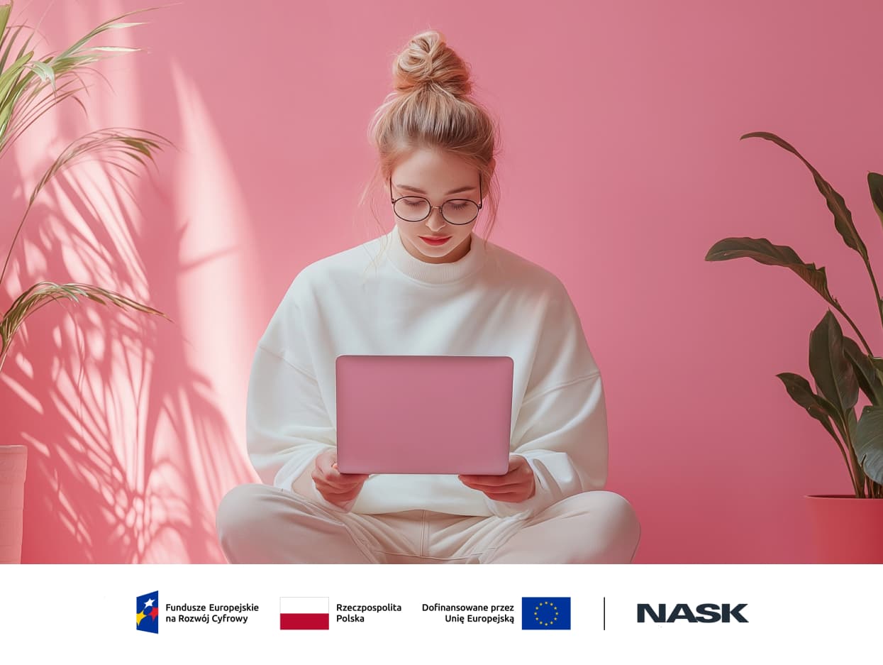 Zdjęcie kobiety, siedzącej ze skrzyżowanymi nogami na tle różowej ściany z różowym tabletem.